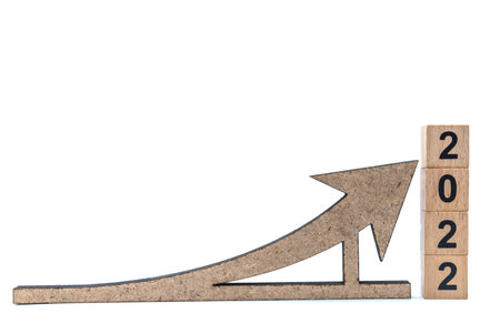 2022 New Year and Business Planning Concept. Closeup of wooden arrow sign and stack of wooden number...