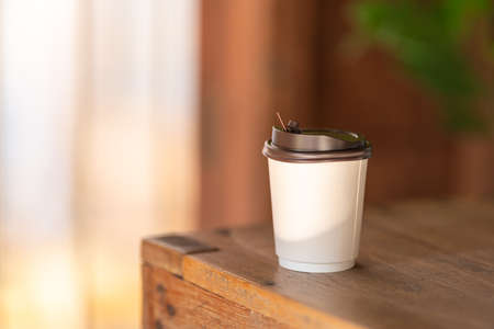 Closeup of disposable take away paper cup of hot coffee on wooden table.の写真素材