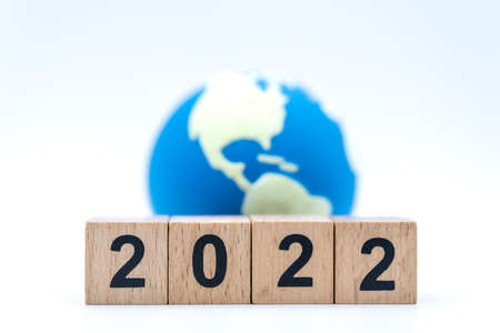 2022 Global and New Year Concept. Closeup of stack of wooden number block with mini world ball on white background.の写真素材