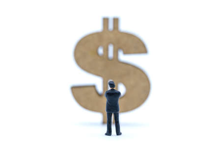 Business, Money Investment and Planning Concept. Businessman miniature figure people figure standing and looking to wooden US Dollar sign on white background.の写真素材