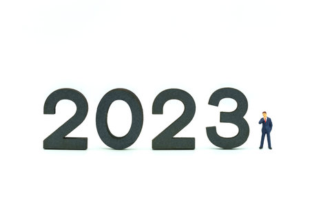2023 New Year and Business Planning Concept. Closeup of businessman miniature figures standing with wooden number block on white background.の写真素材