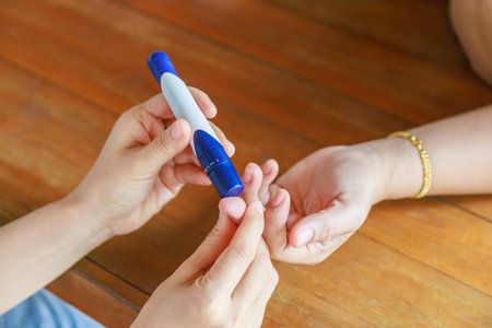 Close up of two woman using lancet on finger to check blood sugar level by Glucose meter using as Medicine, diabetes, glycemia, health care and people concept.の写真素材
