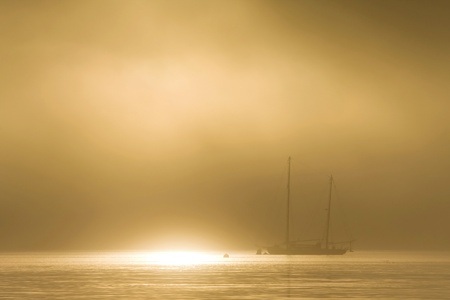Schooner sailboat on a golden foggy dawnの写真素材