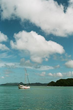 A yacht sailing on a clear day, with blue sky and green waterの写真素材