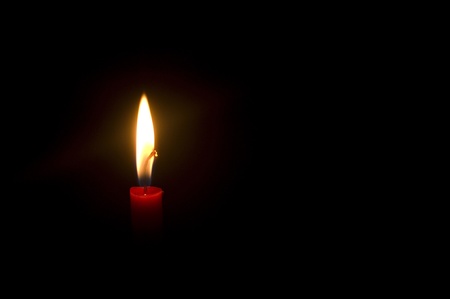 a burning candle in darkness, with copy space.の写真素材