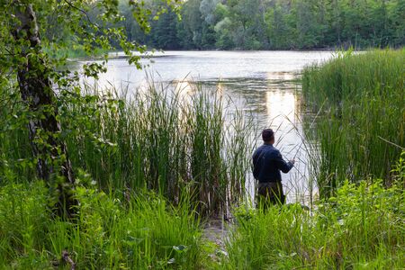 angler standing in the lake and catching the fishの写真素材