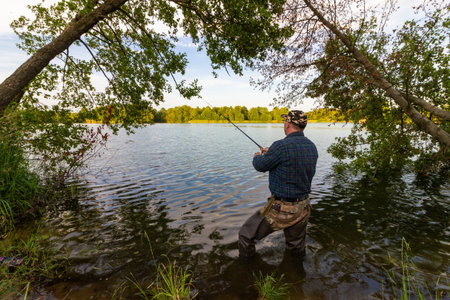 Angler catching the fish in the lake during summer day