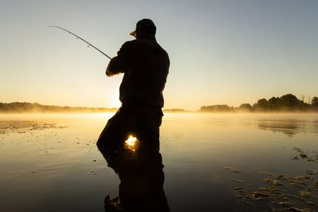 Angler catching the fish during sunriseの写真素材
