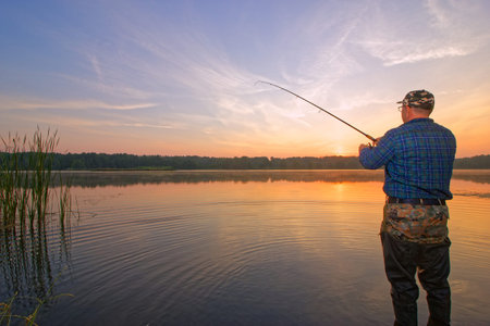 Angler catching the fish in the lake during sunrise