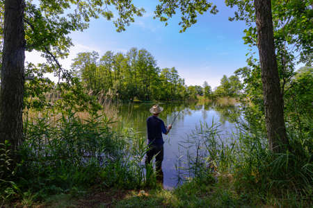 Fisherman catching the fish in the lake during summer sunny dayの写真素材