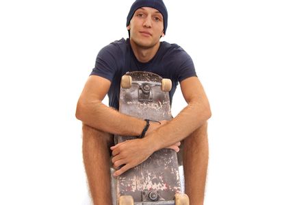 skater with cap sitting with a skate on his kneesの写真素材