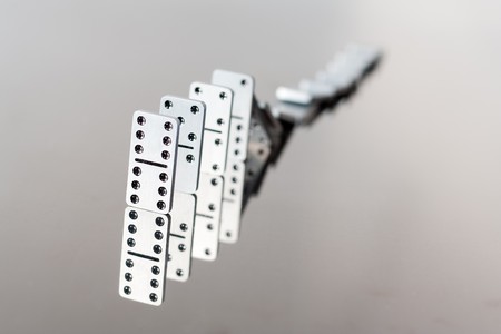 A queue of falling steel dominoes with reflection in polished surfaceの写真素材