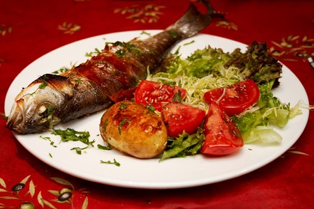 Grilled fish and vegetables served in the restaurantの写真素材