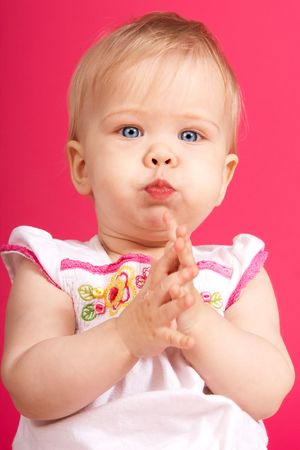 Beautiful babygirl claping one's hands on pink backroundの写真素材
