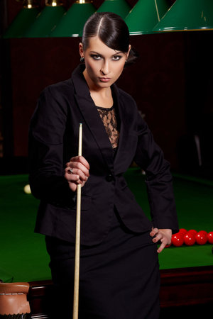 Glamorous brunette sexy woman with cue in snooker club