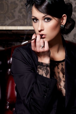 Glamorous brunette woman holding cigarette in mouthpiece in barの写真素材