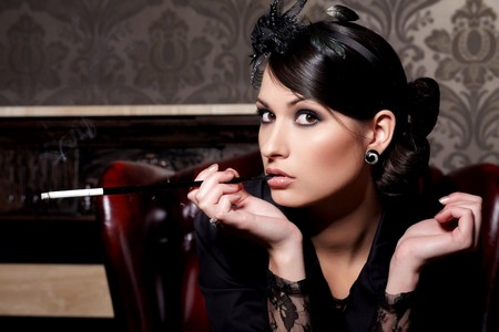 Glamorous brunette woman holding cigarette in mouthpiece in barの写真素材