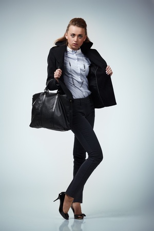 Woman with a bag shirt and wool coat on grey backgroundの写真素材