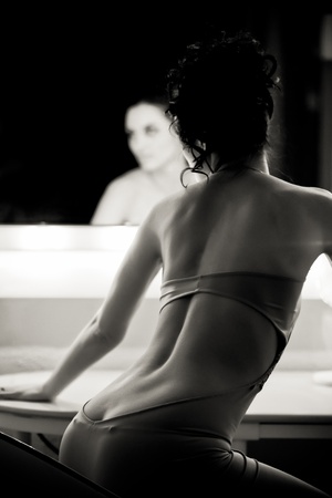 Young woman in pink dress sitting in front of a mirror. Monochrome toningの写真素材