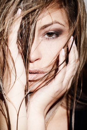 Glamorous young lady touching her hair near white wallの写真素材