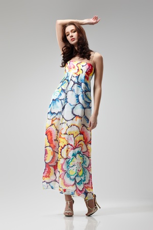 Young beautiful female model in colorful dress on gray backgroundの写真素材