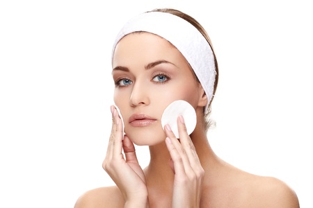 Beautiful young woman applying a creme on her face isolated on white backgroundの写真素材
