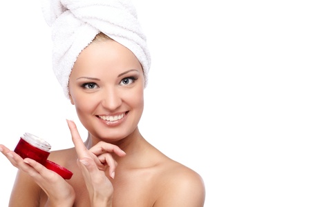 Young beautiful lady with a towel on her head applying cremeの写真素材