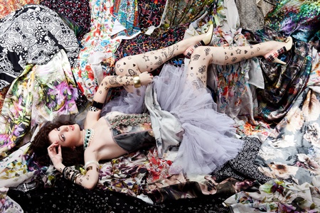 Woman lying on a pieces of colorful fabricsの写真素材