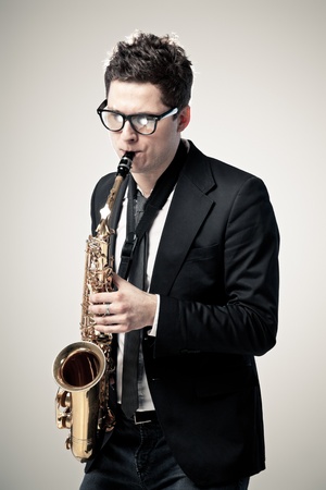 Young man playing sax on gray backgroundの写真素材
