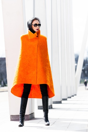 Stylish lady in bright orange coat in a city sceneの写真素材