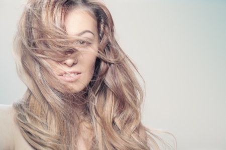 Young brunette lady with a beautiful hair on gray backgroundの写真素材