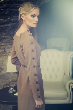 Young blond lady in beige dress posing in vintage interiorの写真素材