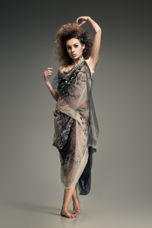 Young brunette lady in fashionable dress posing on grey backgroundの写真素材