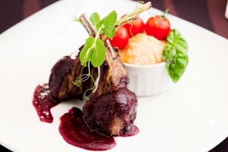 Grilled lamb served with cranberry sauce  tomatoes and potato garnishの写真素材