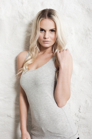 Portrait of a young blond woman leaning on a white wallの写真素材
