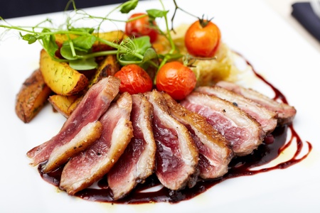 Roasted duck with cherry tomatoes and potatoes marinated in red wineの写真素材