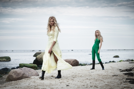 Two fashionable women walking on a beachの写真素材