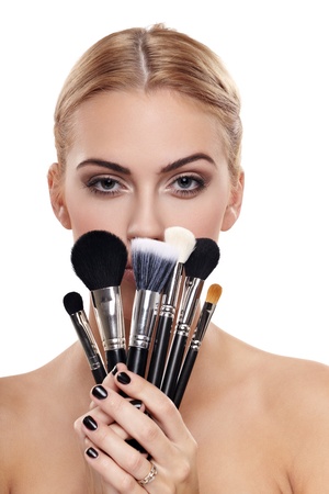 Portrait of beautiful female model holding make-up brushesの写真素材
