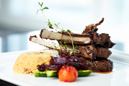 Grilled lamb carre with warm couscous salad, roasted vegetables, Dijon mustard and red wine sauceの写真素材
