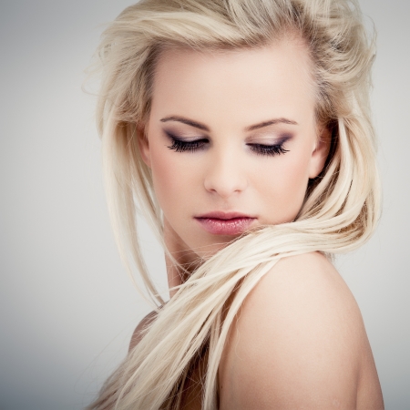 Young blond lady with a beautiful hair on gray backgroundの写真素材