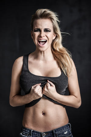 Young blond woman shouting on grey backgroundの写真素材