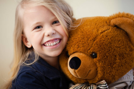 Portrait of an adorable preschool age girl playing with a teddy bearの写真素材