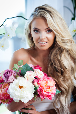 Portrait of attractive blond smiling woman with flowersの写真素材
