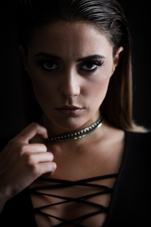 Closeup portrait of a young trendy agressive woman in bodysuit posing near black wallの写真素材