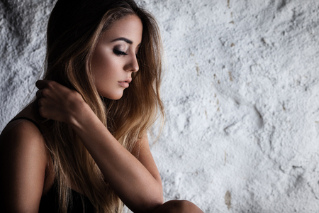 Fashion portrait of beautiful female model posing in black lingerie near white wallの写真素材