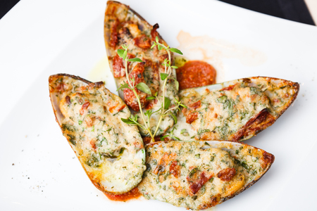 Baked mussels with parmigiano cheese and white wine in tomato coolieの写真素材