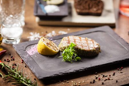Tuna steak with panko and grilled lemon served on a black boardの写真素材