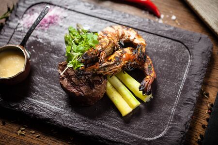 Tasting menu. Beef steak and grilled tiger prawns with asparagus and garlic sauceの写真素材