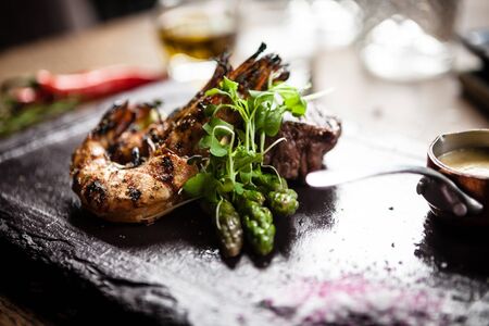 Tasting menu. Beef steak and grilled tiger prawns with asparagus and garlic sauceの写真素材