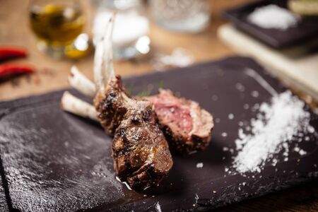 Grilled lamb chops served with a branch of rosemary on a black boardの写真素材